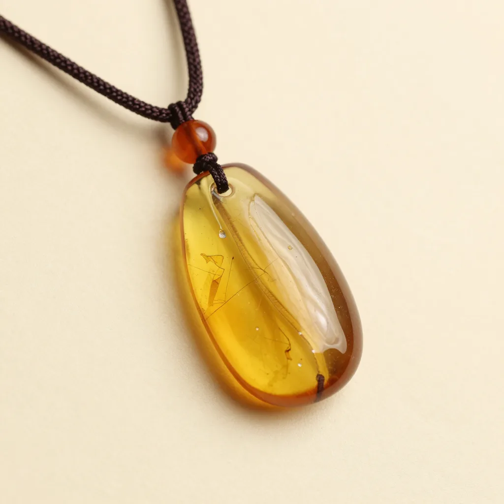 An uncut Baltic amber pendant on a cord on a light background